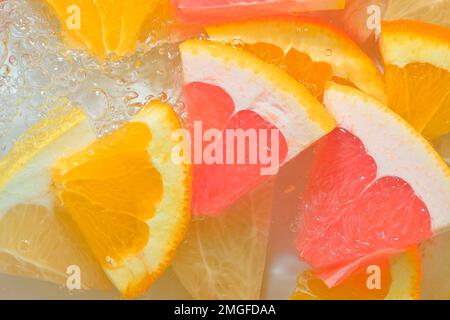 Frische Scheiben saftiger Grapefruit, Orangenfrüchte und Honigpomelo auf weißem Hintergrund. Grapefruitstücke, Orangenfrüchte und Honigpomelo mit Kohlensäure Stockfoto