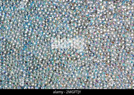 Abstrakter Strasssteinhintergrund. Textur der Strasssteine, die mit weißem Licht beleuchtet werden. Mehrfarbige glänzende Diamanten. Schließen. Leuchtfackeln auf Glas. Stockfoto