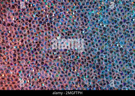Abstrakter Strasssteinhintergrund. Textur von Strasssteinen, die mit mehrfarbigem Licht beleuchtet werden. Rosa und blaue glänzende Diamanten. Schließen. Leuchtfackeln auf Glas. Stockfoto