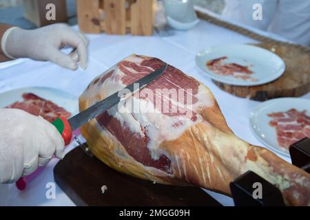 Ein professioneller Koch schneidet iberico-spanischen Schinken in einem Restaurant-Eventtisch Stockfoto