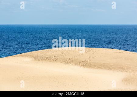 Jemand, der den Ozean von einer Sanddüne in den Dünen von Corralejo, Fuerteventura und den Kanarischen Inseln aus betrachtet. Stockfoto