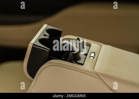 Moderner Getränkehalter für Fahrzeuge in der hinteren Sitzreihe. Armlehne im Auto mit Getränkehalter. Stockfoto