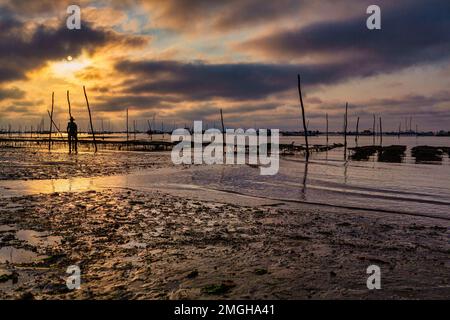 Le Canon (Südwestfrankreich): Sonnenuntergang über der Arcachon Bay. Silhouette einer Statue, die einen Austernfarmer in der Mitte eines Austernbetts darstellt, At Stockfoto