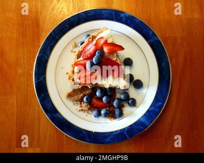 Käsekuchen mit Blaubeeren und Erdbeeren auf einem Teller Stockfoto