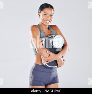 Diät, Porträt und Skalierung mit einer schwarzen Sportlerin im Studio auf grauem Hintergrund für körperliche Positivität oder Gesundheit. Fitness, Gewichtsverlust und Verlieren Stockfoto