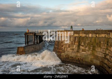 Große Wellen stürzen sich durch die Hafeneingangspiers in Whitby, North Yorkshire, Großbritannien Stockfoto