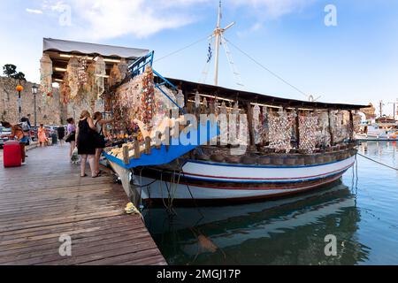 Rhodos, Griechenland - 24. August 2022: Touristenboot ist am Ufer im Hafen von Rhodos, Griechenland, festgemacht. Die Leute kaufen Souvenirs. Stockfoto