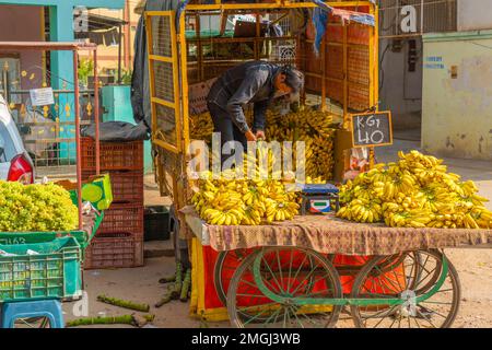 Puttaparthi, Andra Pradesh - Indien - 21,2023. Januar: Ein Mann, der Bananen von einem Tuk Tuk auf einem lokalen indischen Markt verkauft Stockfoto