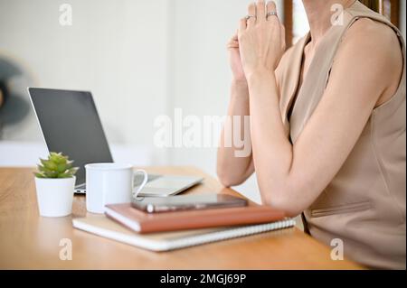 An ihrem Schreibtisch sitzt eine wunderschöne asiatische Geschäftsfrau oder CEO in legerer Kleidung. Zugeschnittenes Bild, Seitenansicht Stockfoto