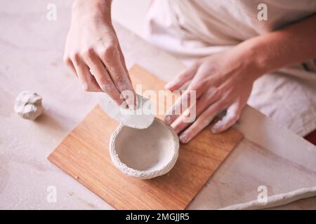 Töpferwerkzeuge, Schüsseln und Hände von Frauen entwerfen Skulpturenformen, kreative Fertigung oder Kunstprodukte. Keramikladen, Kleinunternehmer oder Stockfoto