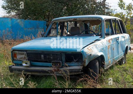 Auf Dem Land. Zerstörte zivile Autos stehen am Straßenrand. Krieg in der Ukraine. Russische Invasion der Ukraine. Kriegsverbrechen Stockfoto