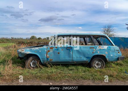 Auf Dem Land. Zerstörte zivile Autos stehen am Straßenrand. Krieg in der Ukraine. Russische Invasion der Ukraine. Kriegsverbrechen Stockfoto