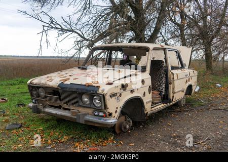 Auf Dem Land. Zerstörte zivile Autos stehen am Straßenrand. Krieg in der Ukraine. Russische Invasion der Ukraine. Kriegsverbrechen Stockfoto