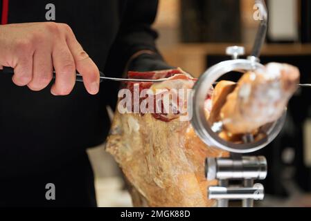 Metzger schneidet Scheiben von spanischem serrano-Schinken Stockfoto