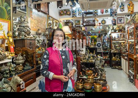 Hongkong - 2022. Dezember Porträt einer Frau, die ein Antiquitätengeschäft in Stanely Market betreibt Stockfoto
