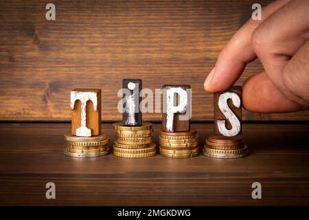 TIPS-Konzept. Text und Geld auf einem holzstrukturierten Hintergrund. Stockfoto