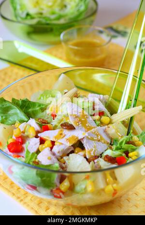 Salat mit gekochtem Hühnerfleisch, Ananas, Rosinen und Mais mit Honig-Senf-Sauce. Garniert mit Sesamsamen Stockfoto