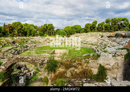 Römisches Amphitheater von Syrakus - I Cent. AD - III Cent. AD - Archäologischer Park Neapolis - Syrakus, Sizilien, Italien das Amphitheater hat zwei Eingänge und wird durch ein komplexes Treppensystem bedient, das von der oberen Ebene absteigt, die sich draußen befindet. Die Arena war im Zentrum mit einem großen rechteckigen Raum ausgestattet, der ursprünglich bedeckt war und über eine unterirdische Passage mit dem südlichen Ende des Denkmals verbunden war, auf der Achse des Eingangskorridors. Rund um die Arena zeichnet sich die Cavea durch ein hohes Podium aus, hinter dem ein überdachter Korridor mit Toren für den Zugang zur Arena für Gladiatoren A verläuft Stockfoto