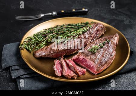 BBQ gegrilltes Bavette Bavet Rindfleisch Steak mit Kräutern auf einem Teller. Schwarzer Hintergrund. Draufsicht. Stockfoto