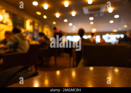 Verschwommenes Hintergrundbild eines Cafés oder Cafés oder Restaurants. Unscharfer Hintergrund mit Bokeh. Stockfoto