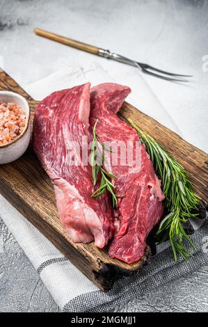 Fleischer wählen Bavette rohes Rindfleisch Steak oder Flankenklappe auf einem Holzbrett mit Kräutern. Weißer Hintergrund. Draufsicht. Stockfoto