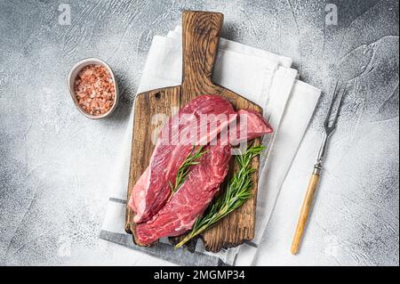 Fleischer wählen Bavette rohes Rindfleisch Steak oder Flankenklappe auf einem Holzbrett mit Kräutern. Weißer Hintergrund. Draufsicht. Stockfoto