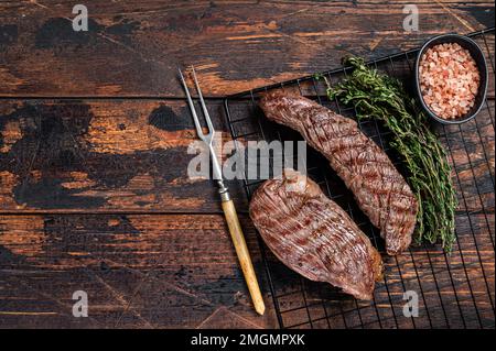 Gegrillte Sirloin Lap oder Bavette-Rindfleisch-Steak auf einem Grill mit Kräutern. Holzhintergrund. Draufsicht. Speicherplatz kopieren Stockfoto