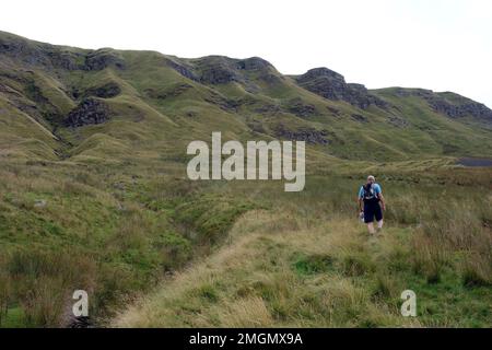 Mann, der an den Crags am Mallerstang Edge von Outhgill zum High Seat am Mallerstang Common im Eden Valley, Yorkshire Dales National Park, Großbritannien, vorbeigeht. Stockfoto