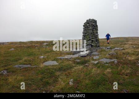 Mann zu Fuß zu einem Cairn auf 'Archy Styrigg' (Gregory Chapel) zwischen High Seat & Hugh Seat über Mallerstang Common im Eden Valley, Yorkshire Dales. Stockfoto