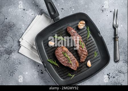 Geröstet auf einer gegrillten Pfannenflanke oder Bavette-Rindfleisch-Steak mit Rosmarin. Grauer Hintergrund. Draufsicht Stockfoto