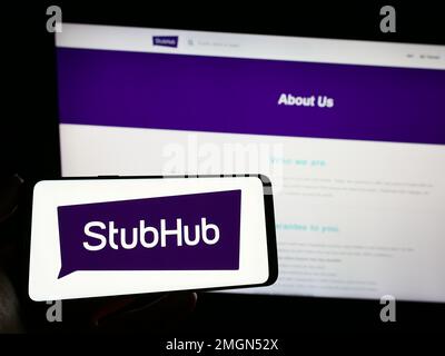 Person, die ein Mobiltelefon mit dem Logo des amerikanischen Ticketunternehmens StubHub auf dem Bildschirm vor der geschäftlichen Webseite hält. Konzentrieren Sie sich auf das Display des Telefons. Stockfoto