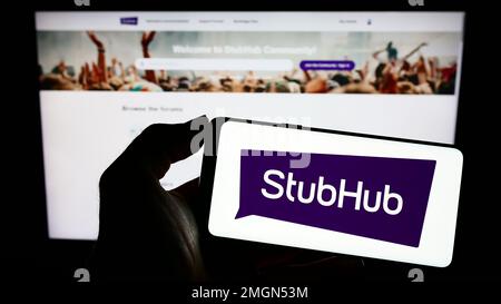 Person, die ein Mobiltelefon mit dem Logo des US-amerikanischen Ticketunternehmens StubHub auf dem Bildschirm vor der Unternehmenswebseite hält. Konzentrieren Sie sich auf das Display des Telefons. Stockfoto