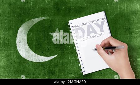 Menschliche Hand schreibt etwas in ein Notizbuch. Tag Der Pakistanischen Resolution Stockfoto