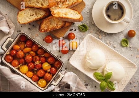 Mittagessen - Burrata-Käse mit gebackenen Tomaten und Toast. Stockfoto