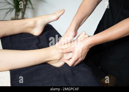 Professionelle Therapeutin, die einem Mädchen eine traditionelle thailändische Fußmassage gibt Stockfoto