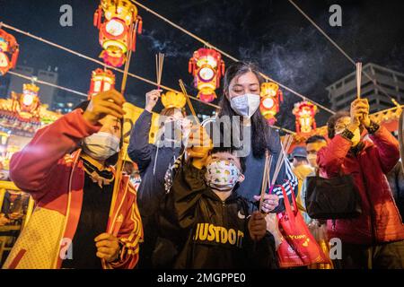 Mutter und ihre beiden Kinder verbrennen ihre Joss-Stäbchen, um im Wong Tai Sin Tempel in Hongkong zu beten. Die Menschen strömten zum Tempel der Wong Tai Sin, um zum ersten Mal seit drei Jahren seit der COVID-Pandemie zu beten, als sie sich versammelten, um ihre ersten Joss-Stäbe zu verbrennen, um das Mondneujahr und das Jahr des Hasen im chinesischen Tierkreislauf zu feiern. Stockfoto