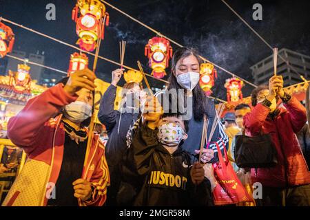 Hongkong, Hongkong. 21. Januar 2023. Mutter und ihre beiden Kinder verbrennen ihre Joss-Stäbchen, um im Wong Tai Sin Tempel in Hongkong zu beten. Die Menschen strömten zum Tempel der Wong Tai Sin, um zum ersten Mal seit drei Jahren seit der COVID-Pandemie zu beten, als sie sich versammelten, um ihre ersten Joss-Stäbe zu verbrennen, um das Mondneujahr und das Jahr des Hasen im chinesischen Tierkreislauf zu feiern. (Kreditbild: © Alex Chan Tsz Yuk/SOPA Images via ZUMA Press Wire) NUR REDAKTIONELLE VERWENDUNG! Nicht für den kommerziellen GEBRAUCH! Stockfoto