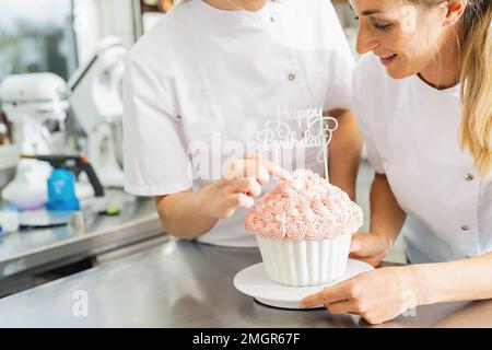 Süßigkeiten schmücken große Geburtstagskuchen-Muffins mit Süßigkeiten in der Bäckerei Stockfoto