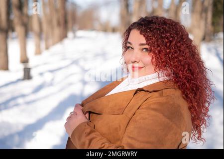 Eine fröhliche, fette Kaukasierin spaziert im Winter im Park. Stockfoto