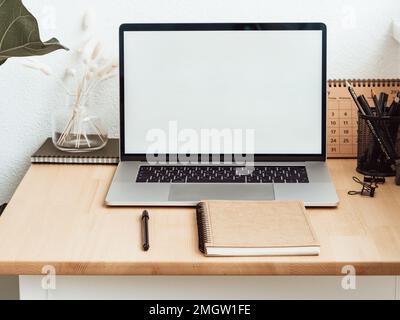 Home Office Holzschreibtisch mit offenem Laptop mit weißem leeren Bildschirm für Text. Vorderansicht. Speicherplatz kopieren Stockfoto