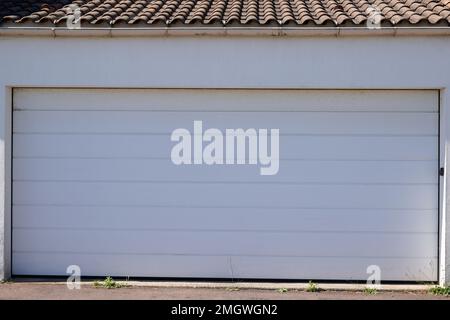 Großes, geteiltes Garagentor weiß an der Fassade des Gebäudes geschlossen Stockfoto