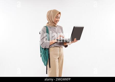 Eine wunderschöne Schülerin mit Hijab-Stand öffnete den Laptop mit ihrer Hand Stockfoto