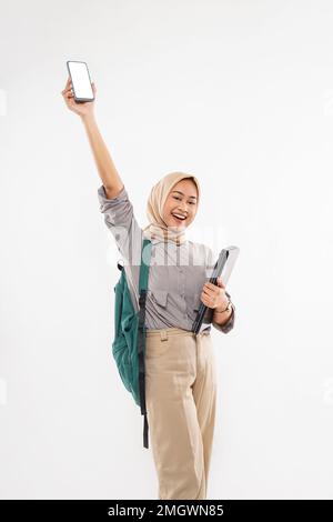 Eine Studentin mit Hidschab, die steht und das Telefon hebt Stockfoto