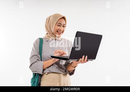 Eine Studentin mit einem lächelnden Hijab, während sie den Laptop öffnete Stockfoto