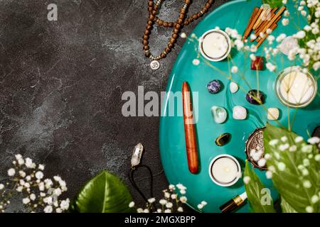 Pflegeleichte, heilende Komposition mit Rosenkranz, Duftstäbchen, Chakra-Steinen, Sandelholz-Stäbchen und Kerze auf einem grünen Marmorpodium. Konzept der Entspannung Stockfoto