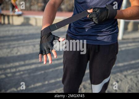 Nahaufnahme der Hand eines Sportlers, der Schutzhandschuhe anlegt, um im Fitnessstudio zu trainieren Stockfoto