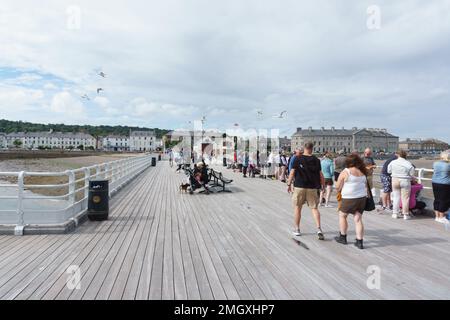 Touristen und Besucher genießen einen Sommernachmittag am Beaumaris Pier, einer beliebten Touristenattraktion am Meer auf der Insel Anglesey Wales Stockfoto