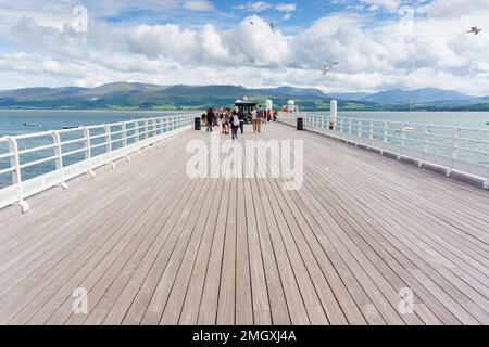 Touristen und Besucher genießen einen Sommernachmittag am Beaumaris Pier, einer beliebten Touristenattraktion am Meer auf der Insel Anglesey Wales Stockfoto