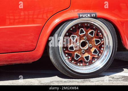 Nahaufnahme des glänzenden Rads eines abgestimmten roten Autos mit tiefer Landung. Stockfoto