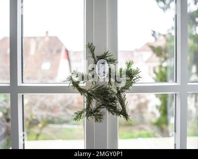 Weihnachtsstern am Holzfenster, auf traditionellem nordischem Porzellan mit Gänsebild aufgehängt Stockfoto